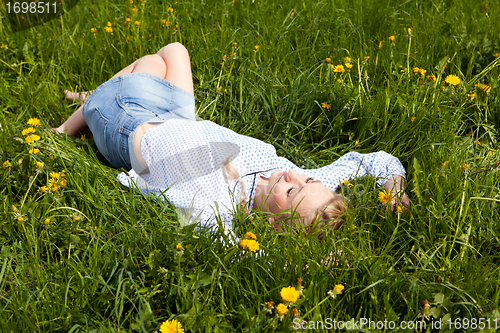 Image of young woman lying in green gras happy
