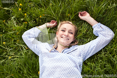 Image of young woman lying in green gras happy