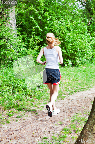Image of young woman is jogging in forest