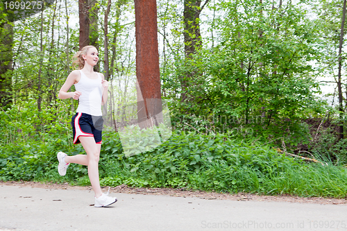 Image of young woman is jogging in forest