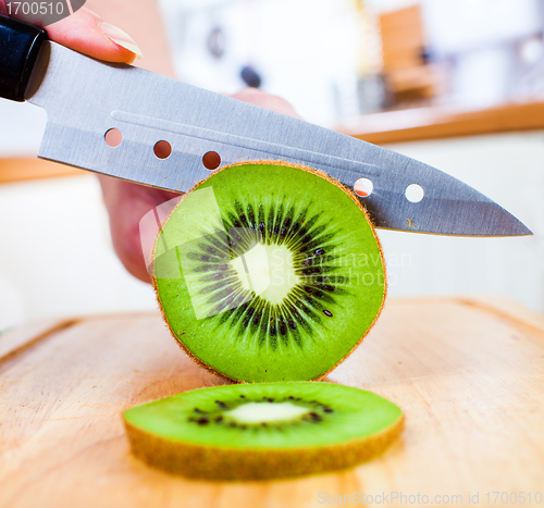 Image of Woman's hands cutting kiwi