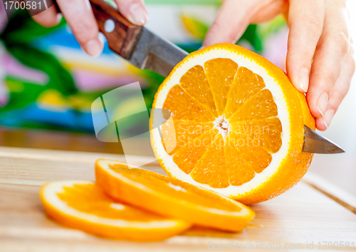 Image of Woman's hands cutting orange