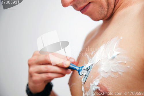 Image of Young man shaving his chest, torso