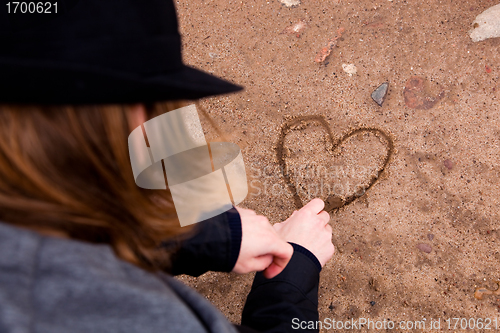 Image of Young man drawing heart on ground