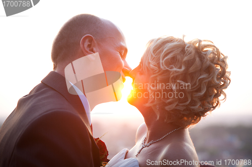 Image of Bride and groom kissing at sunset