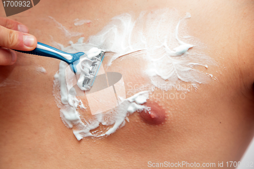 Image of Young man shaving his chest, torso