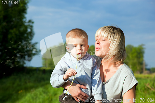 Image of Kid and mother blowing dandelion