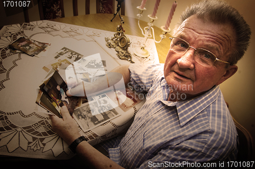 Image of Senior man looking at old photographs.