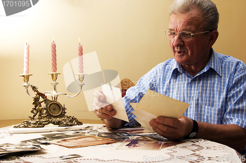 Image of Senior man looking at old photographs.