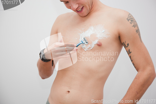 Image of Young man shaving his chest, torso