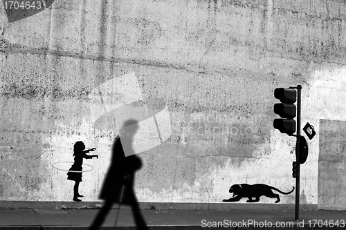 Image of Silhouette passing by a wall with graffitis