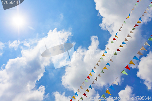 Image of Blue sky with multi colored party flags hanging 
