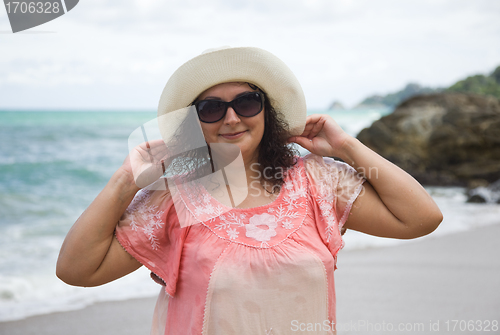 Image of A woman in a white hat and sunglasses on the beach