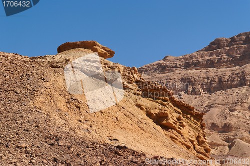 Image of Weathered orange rock on top of dune in desert canyon