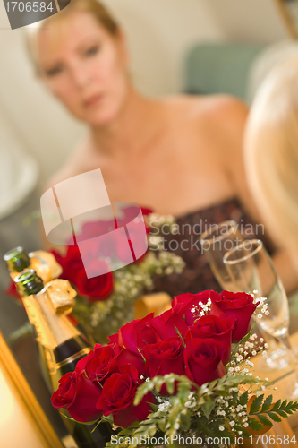 Image of Pensive Blonde Sits at Mirror Near Champagne and Roses