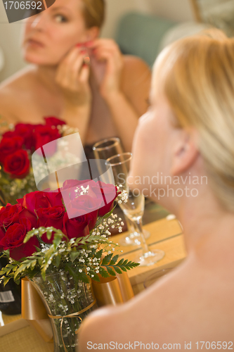 Image of Blonde Woman Applies Makeup at Mirror Near Champagne and Roses