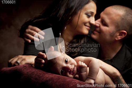 Image of Mixed Race Couple Lovingly Look On While Baby Lays on Pillow