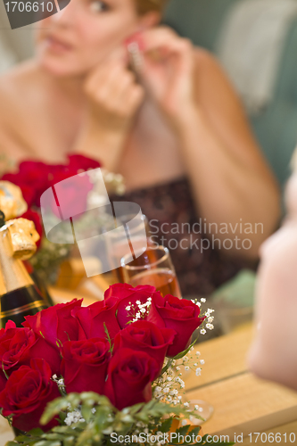 Image of Blonde Woman Applies Makeup at Mirror Near Champagne and Roses