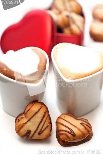 Image of heart shaped cream cookies on red heart metal box and coffee