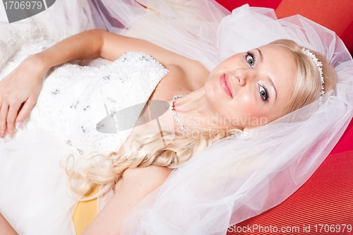 Image of beautiful  bride lying on red sofa