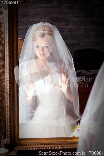 Image of beautiful bride in white infront of mirror