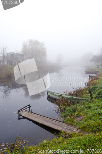 Image of Wooden boat and bridge on river sunken in fog 