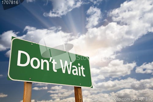 Image of Don't Wait Green Road Sign and Clouds