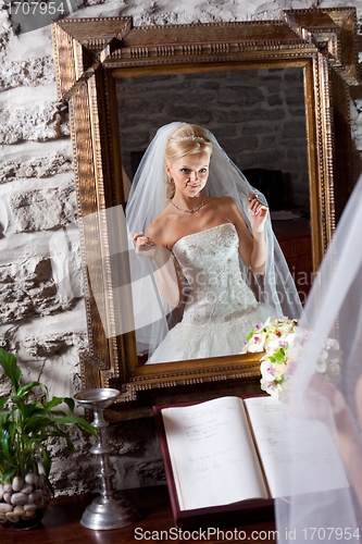 Image of beautiful bride in white in front of mirror
