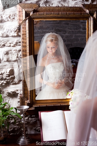 Image of beautiful bride in white in front of mirror