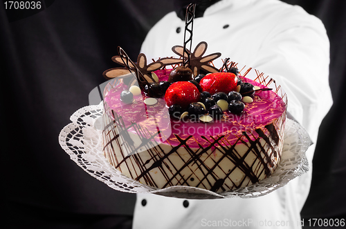 Image of Holding cake against dark background