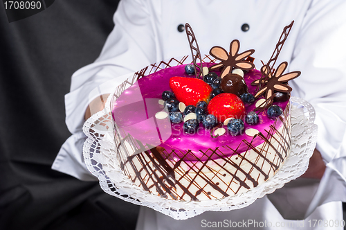 Image of Holding cake against dark background