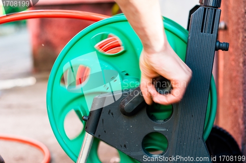 Image of Man rolling up garden hose