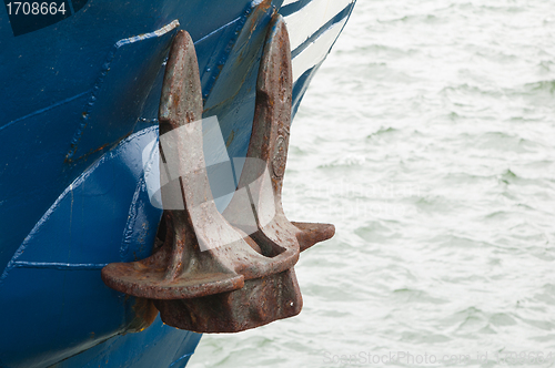 Image of Old rusty anchor at a board of the ship