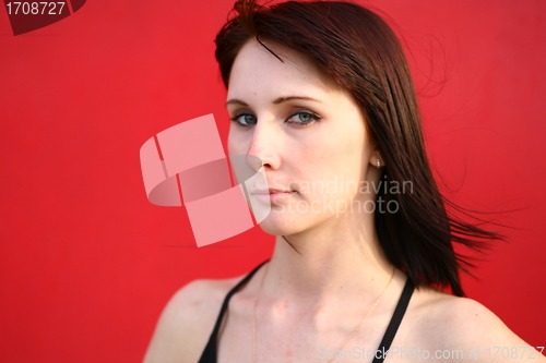 Image of girl is posing against red wall