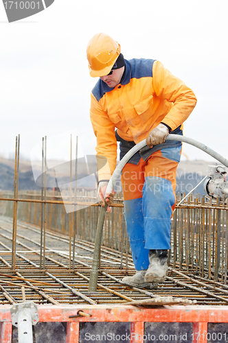 Image of builder worker pouring concrete into form