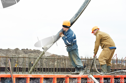 Image of builder worker pouring concrete into form