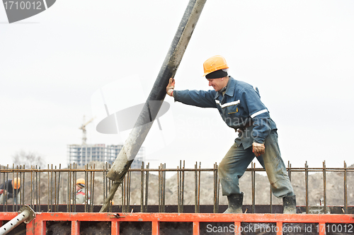 Image of builder worker pouring concrete into form