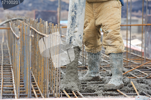 Image of builder worker pouring concrete into form