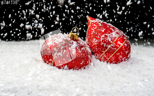 Image of Snow falling on two red ornaments