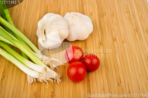 Image of Green Onions, Tomatoes, and Garlic on Cutting Board