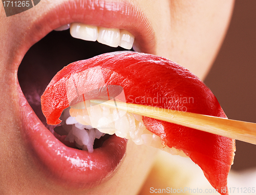 Image of Beautiful young woman eating sushi