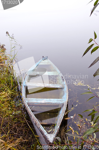 Image of Sunken wooden boat with water stand on river shore 