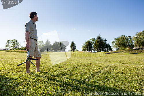 Image of Senior man cutting grass with shears