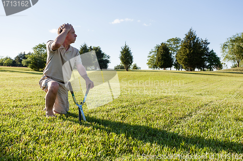 Image of Senior man cutting grass with shears