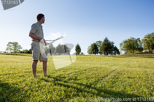 Image of Senior man cutting grass with shears