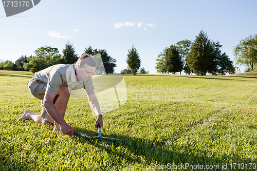 Image of Senior man cutting grass with shears