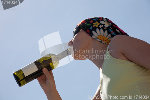 Image of profile of woman drinking from wine bottle