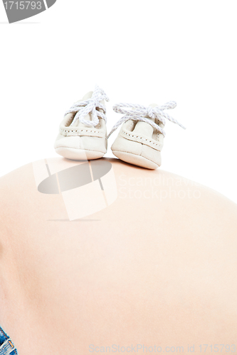 Image of tummy of pregnant woman with small boots on isolated white
