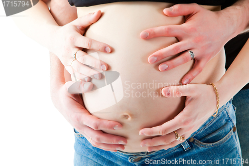Image of Caring hands of parents embracing tummy of pregnant mother
