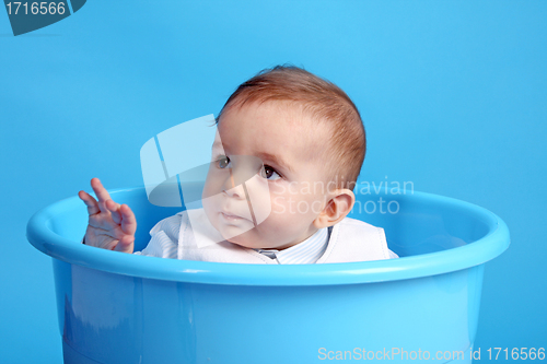 Image of Portrait of a happy baby boy on blue bucket isolated on blue bac